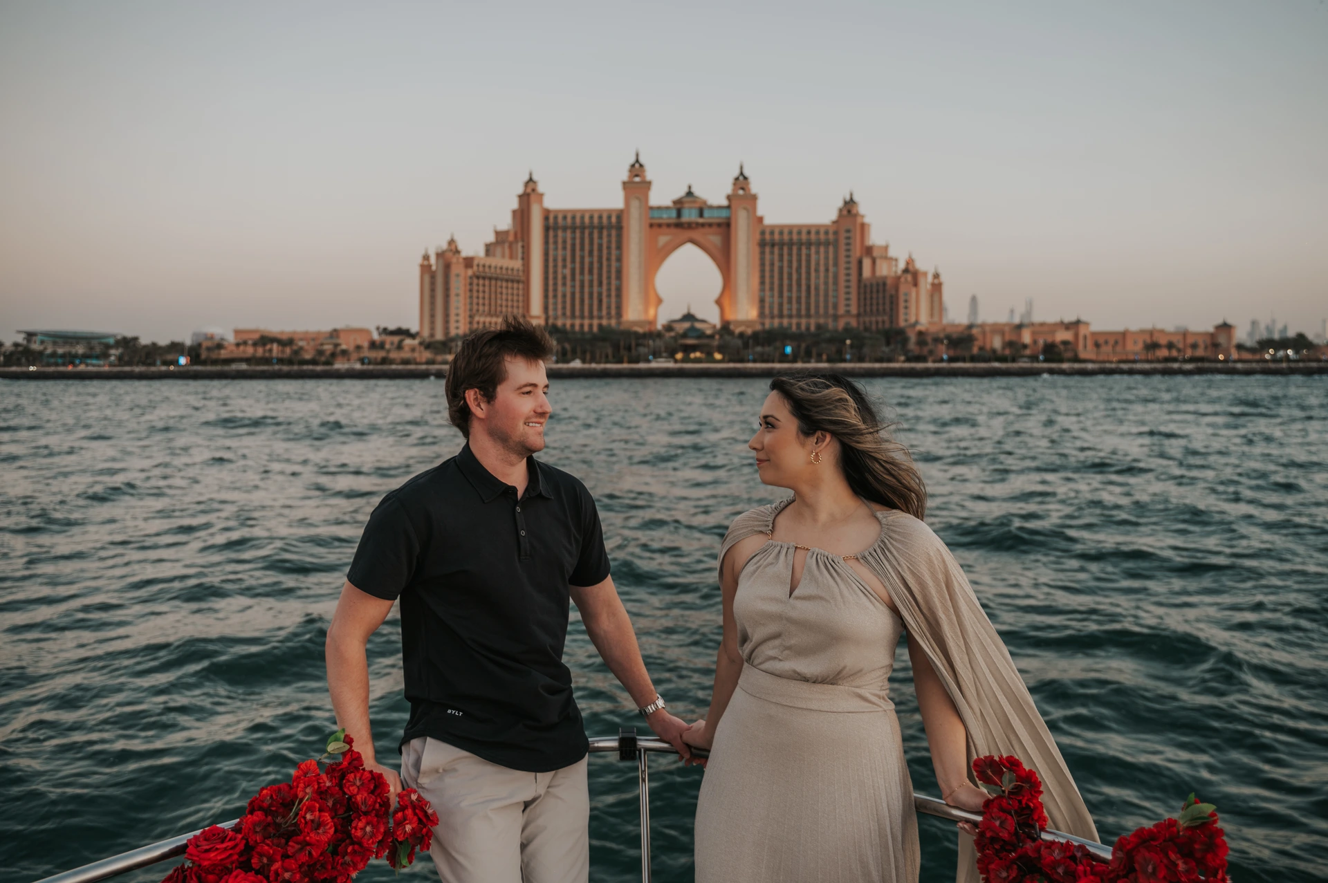 A couple walks together by the water with Atlantis The Palm visible in the background.