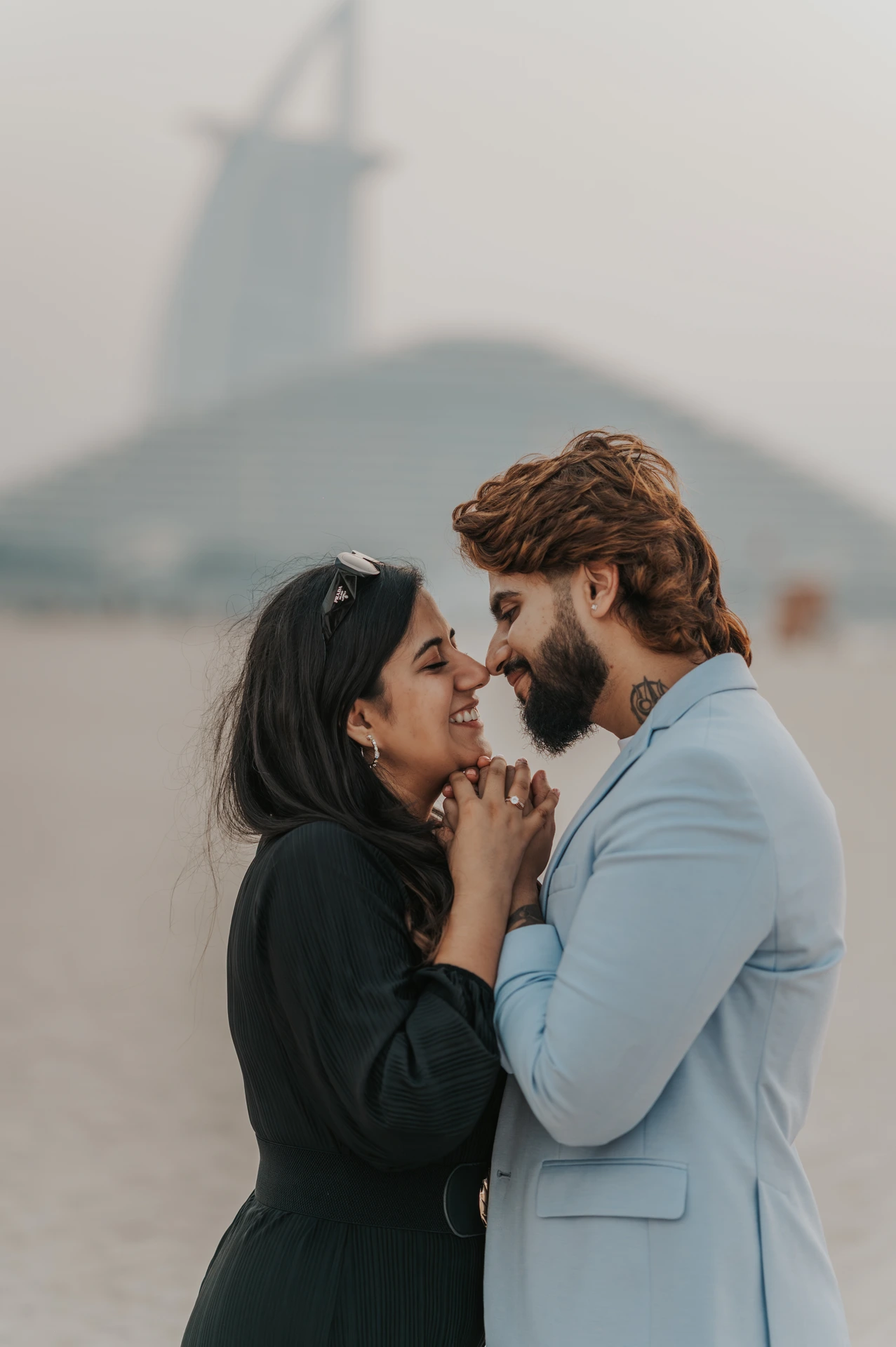 A close portrait of a couple smiling together on a Dubai beach in warm natural light.