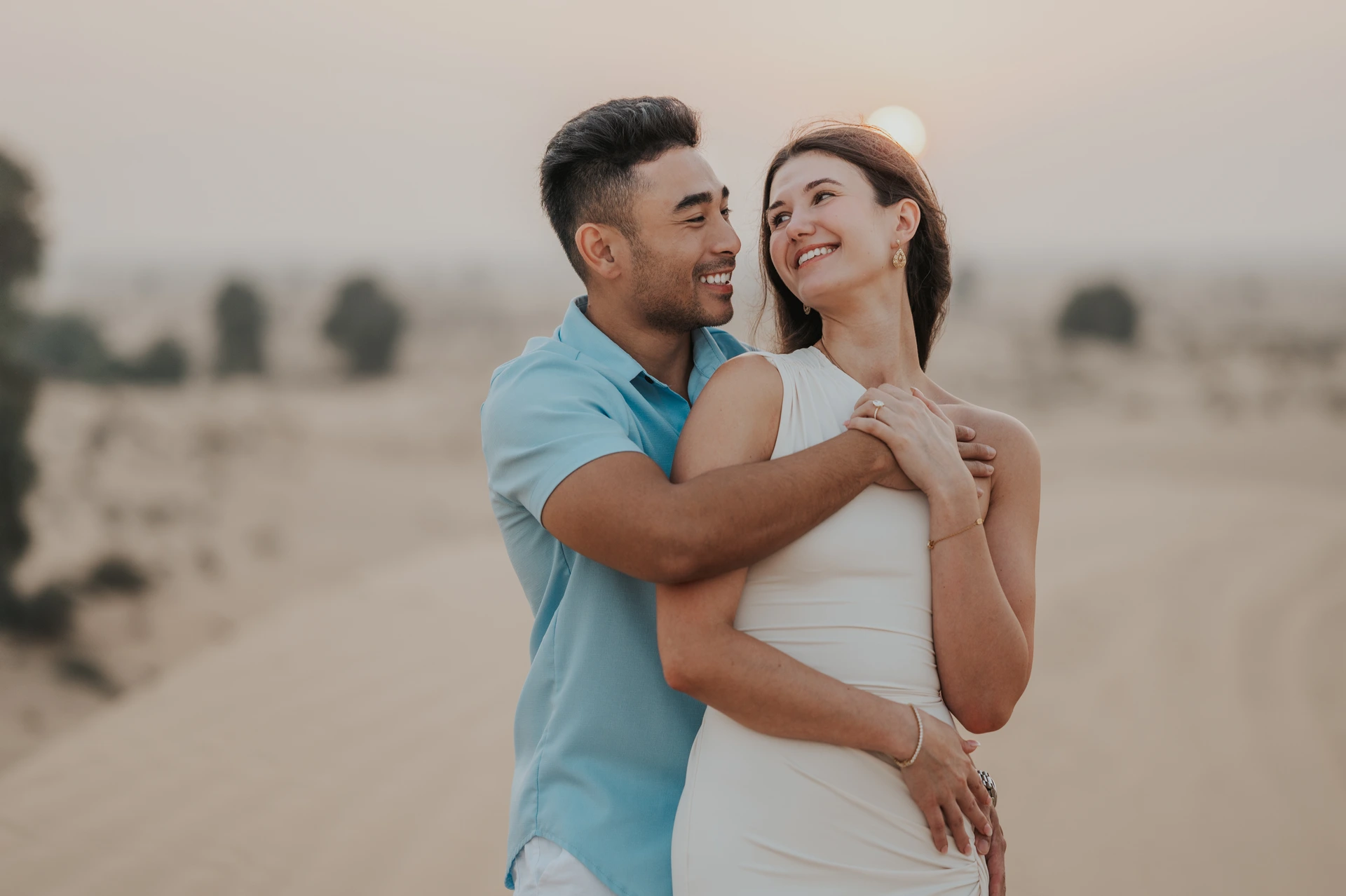 Couple photoshoot ideas Dubai - Desert golden-hour embrace A couple embraces on Dubai desert dunes at golden hour during a romantic photoshoot.
