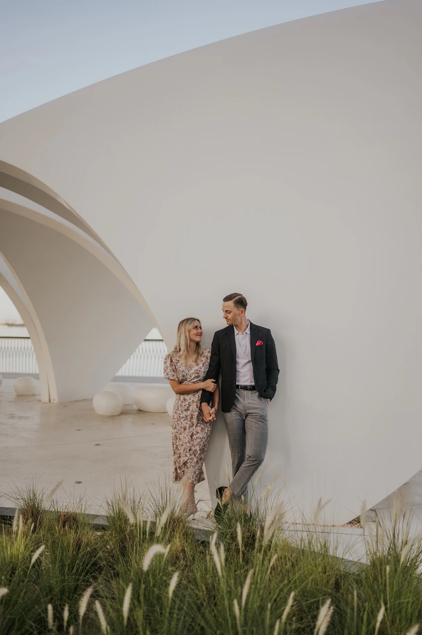 Couple photoshoot dubai costs - City architecture couple portrait A couple stands beneath modern curved architecture in Dubai during an urban-style photoshoot.