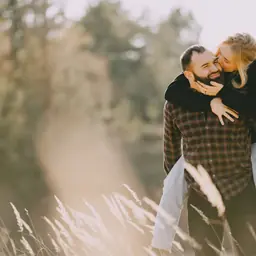 Couple in grain field laughing at eachother