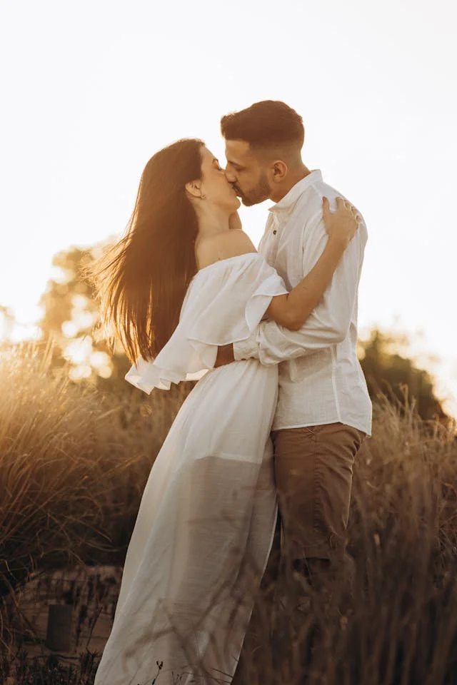 Couple kissing in grain field with sun going down
