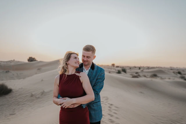 Desert couple photoshoot Dubai dunes A couple embraces on rolling Dubai desert dunes at golden hour during a romantic desert couple photoshoot.