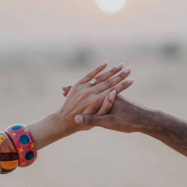 Dubai desert proposal Hand with diamond ring during Dubai desert proposal against the setting sun