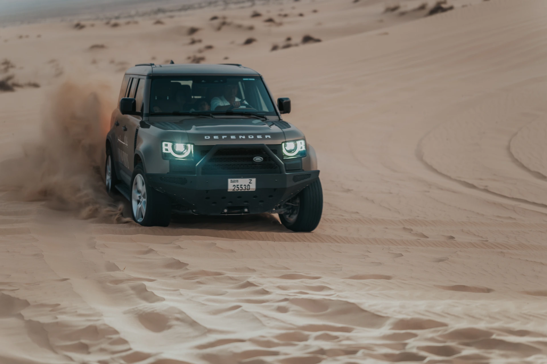 A dark SUV driving across Dubai dunes, often used for desert proposal transport and setup access.