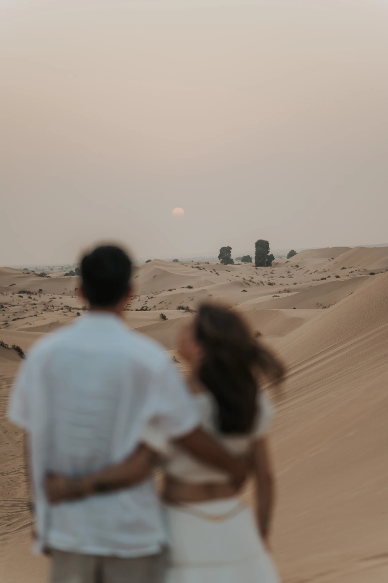 Kosinta Dubain aavikolla Pari näkyy epätarkkana etualalla ja aurinko tarkkana taustalla kosinnan aikana Dubain aavikolla
