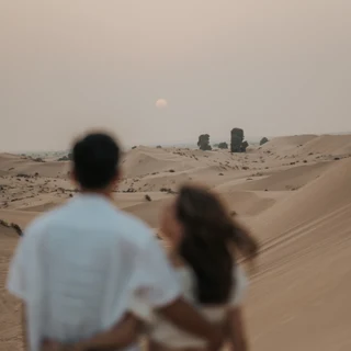 Couple photographed from behind after their proposal in the desert with the sun going down