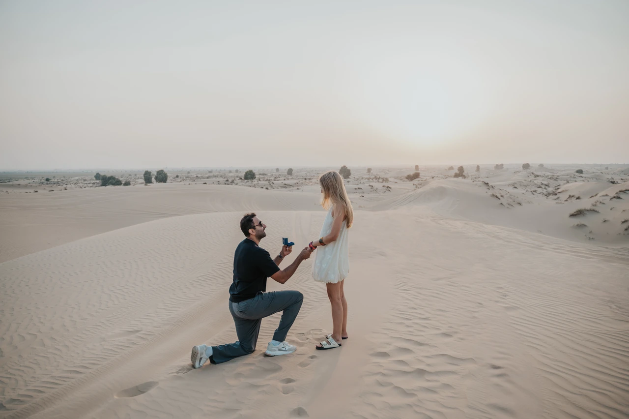Desert Proposal Guide Dubai - Sunset Couple Stroll A couple strolls hand in hand on Dubai dunes at sunset after a proposal moment.