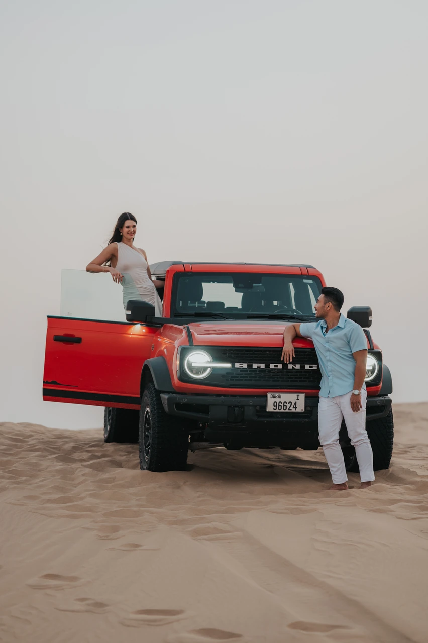 When to go desert photoshoot Dubai Couple with red jeep in Dubai desert during golden hour