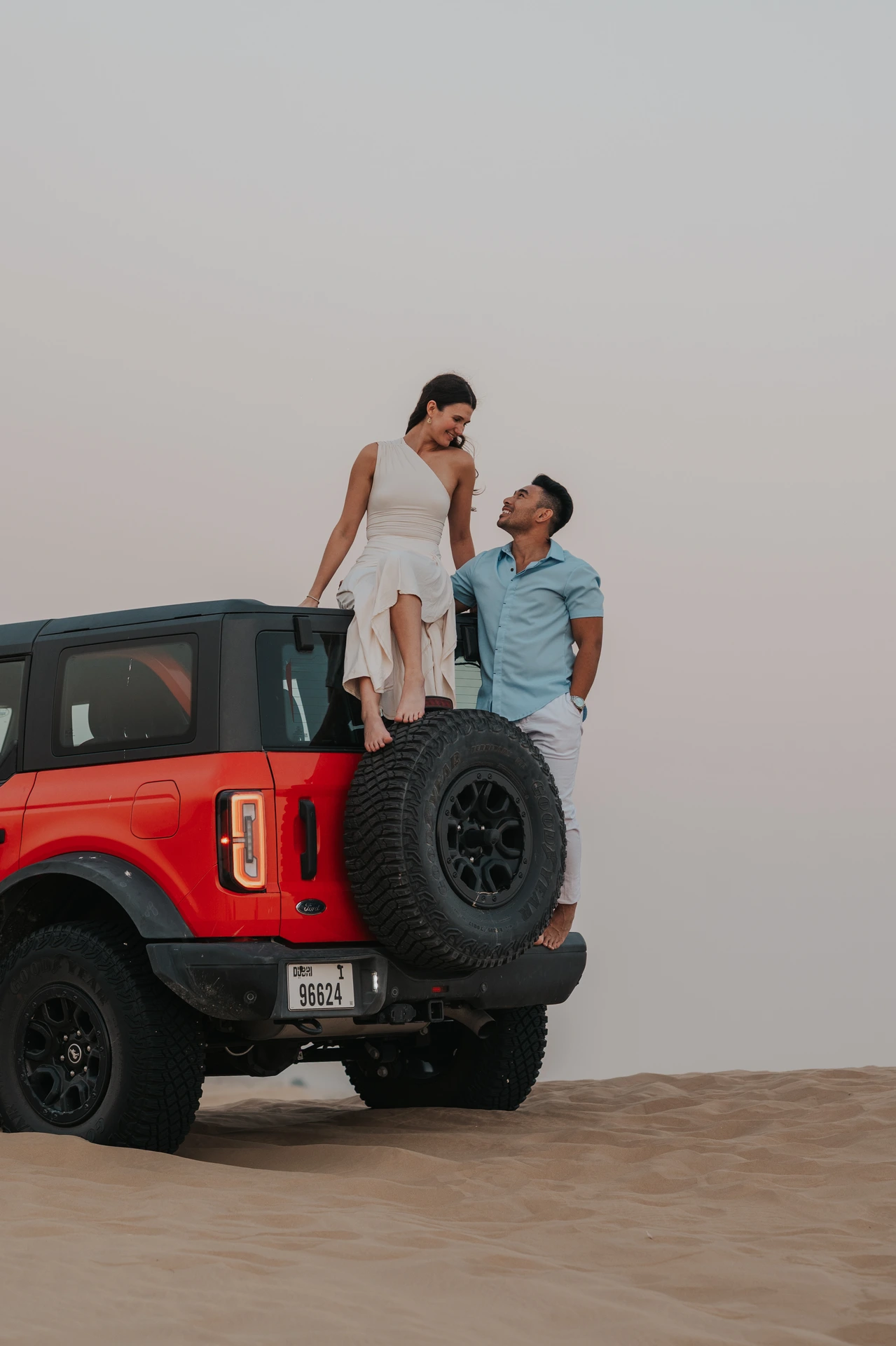 Couple on red jeep in Dubai desert at sunset
