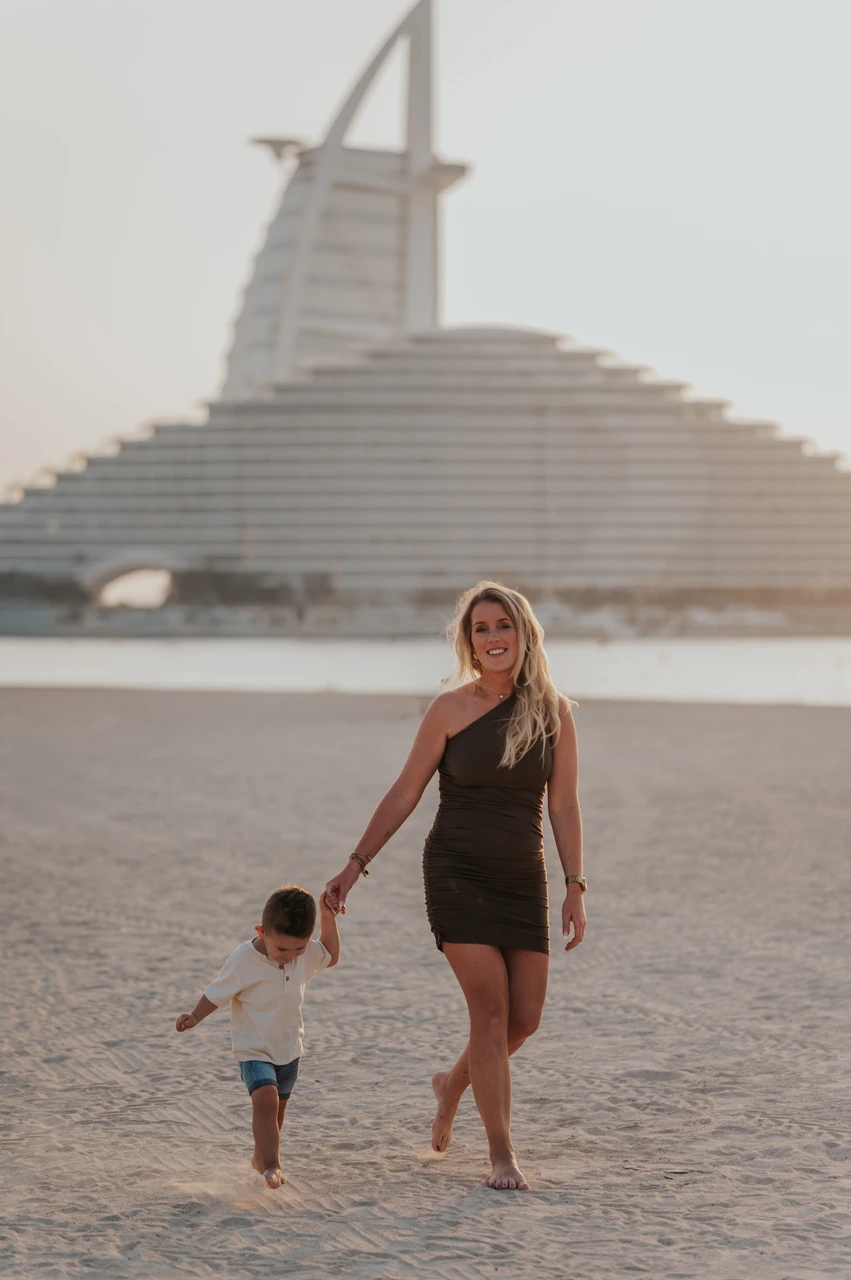 Dubai beach photoshoot guide - portrait near Jumeirah Beach Hotel A woman walks on Dubai beach near Jumeirah Beach Hotel during a beach photoshoot with soft evening light.