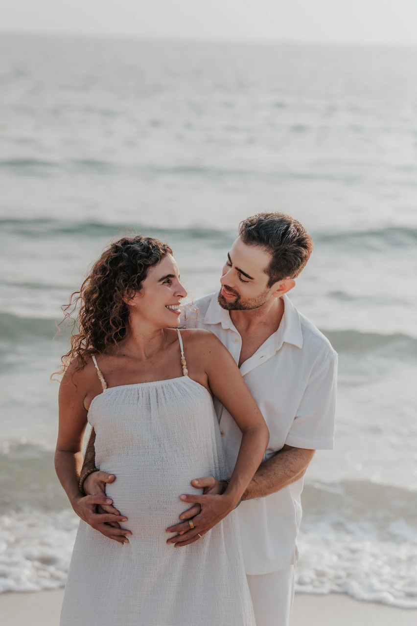 Best maternity photoshoot locations Dubai - Beach close-up smile A close-up of an expecting couple smiling together by the sea during a Dubai maternity session.