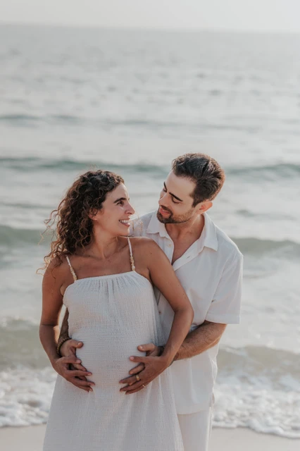 A close-up of an expecting couple smiling together by the sea during a Dubai maternity session.