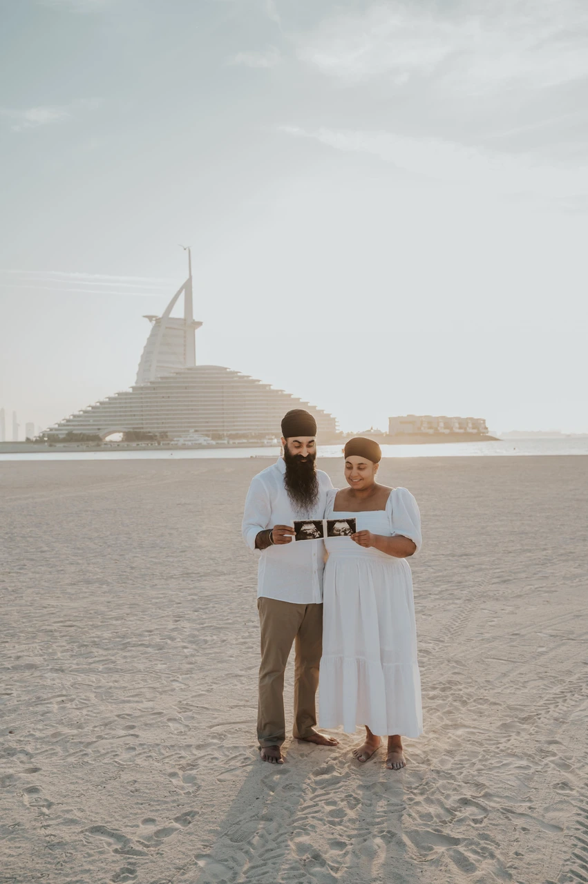 Burj Al Arab maternity photoshoot Dubai - timing guide example An expecting couple stands on Dubai beach with Burj Al Arab behind them during a maternity photoshoot used for timing guidance.