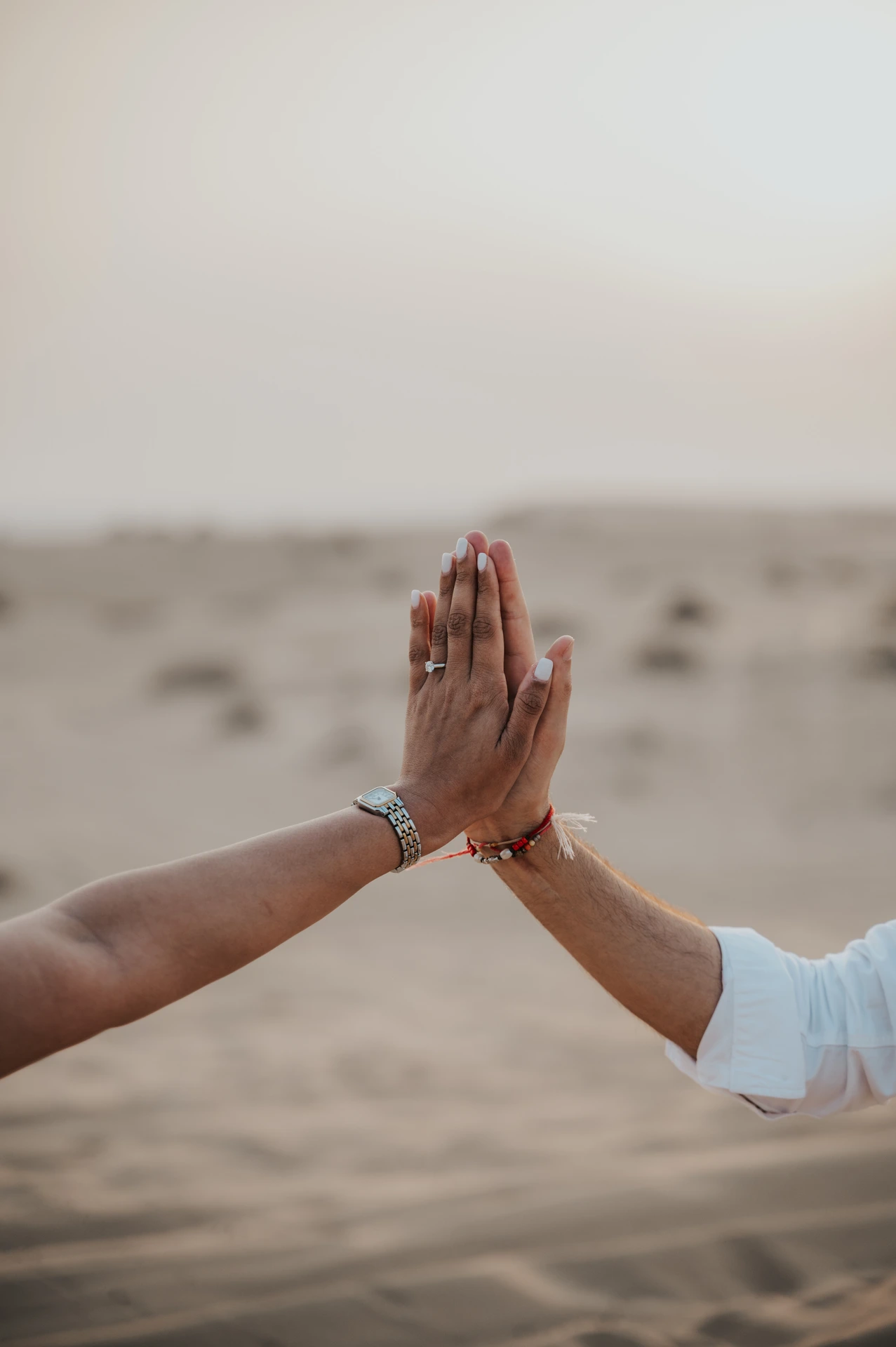 Hand with diamond ring during Dubai desert proposal against the setting sun