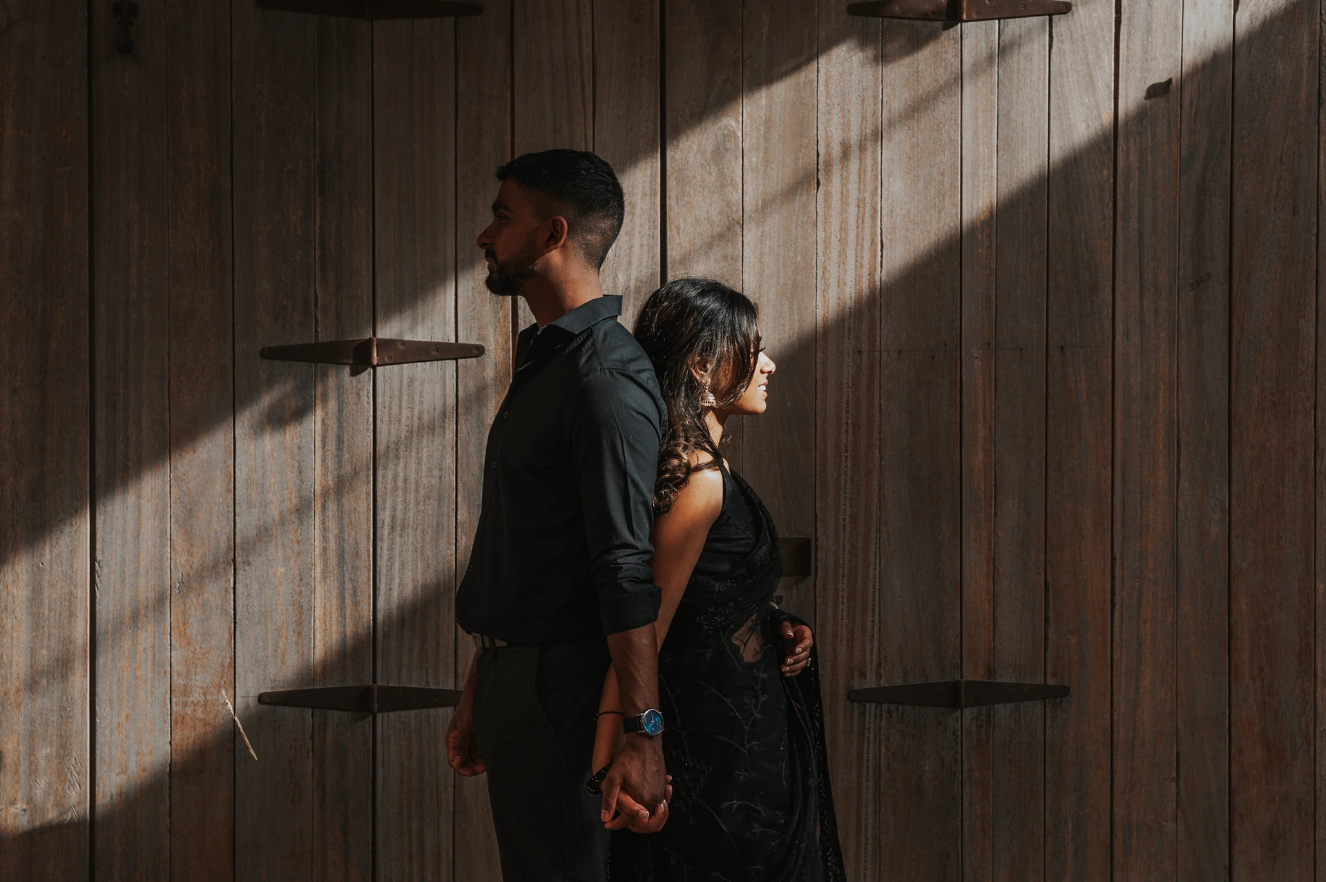 An engaged couple poses in Al Seef Old Dubai during an engagement photoshoot, framed by heritage architecture and warm textured backgrounds.