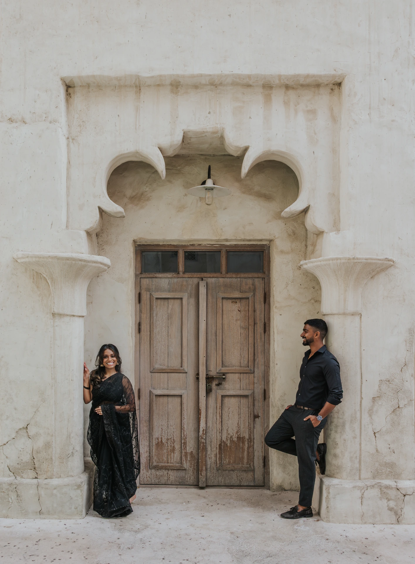 Dubai Engagement Photoshoot - Old Dubai heritage lane An engaged couple stands in Old Dubai during an engagement photoshoot, using heritage textures and warm architecture for timeless travel portraits.