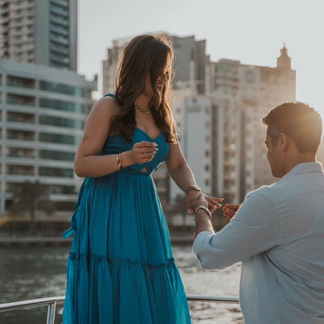 Huwelijksaanzoek fotograaf Dubai Een man die zijn partner ten huwelijk vraagt op een boot in Dubai, met de Dubai Marina op de achtergrond, vastgelegd door een huwelijksaanzoek fotograaf in Dubai.
