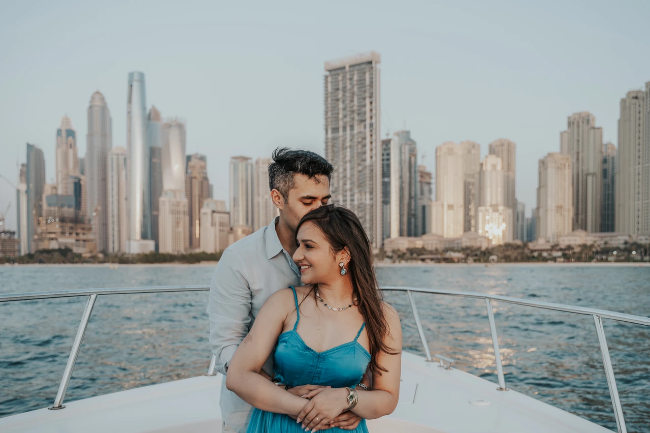 Dubai Marina proposal skyline portraits A couple embracing on a yacht with Dubai Marina skyline behind them during a sunset proposal photoshoot.