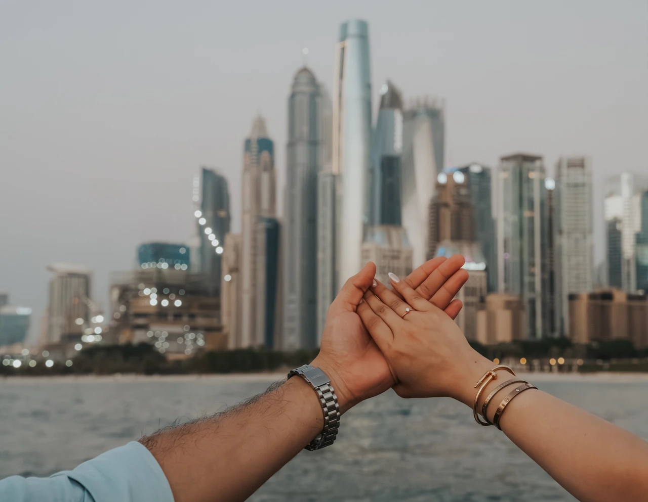 Dubai Marina proposal detail shot Close-up of interlocked hands beside Dubai Marina water during a romantic proposal photoshoot.