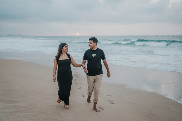 An expecting couple walks along the Dubai shoreline during a maternity photoshoot, showing movement and connection in an outdoor beach session.
