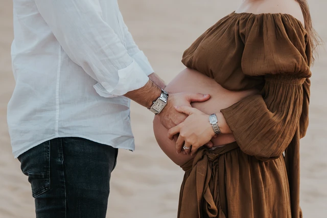 A close portrait shows a pregnant woman and her partner on Dubai beach at sunset, creating a warm maternity photoshoot close-up with soft tones.