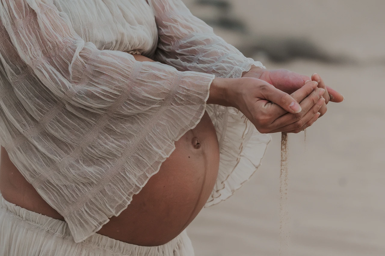 Maternity Shoot Outfit Dubai - bump detail sleeve texture A close-up shows a pregnant belly and textured sleeve fabric during a Dubai maternity shoot, highlighting outfit detail and soft neutral material choices.