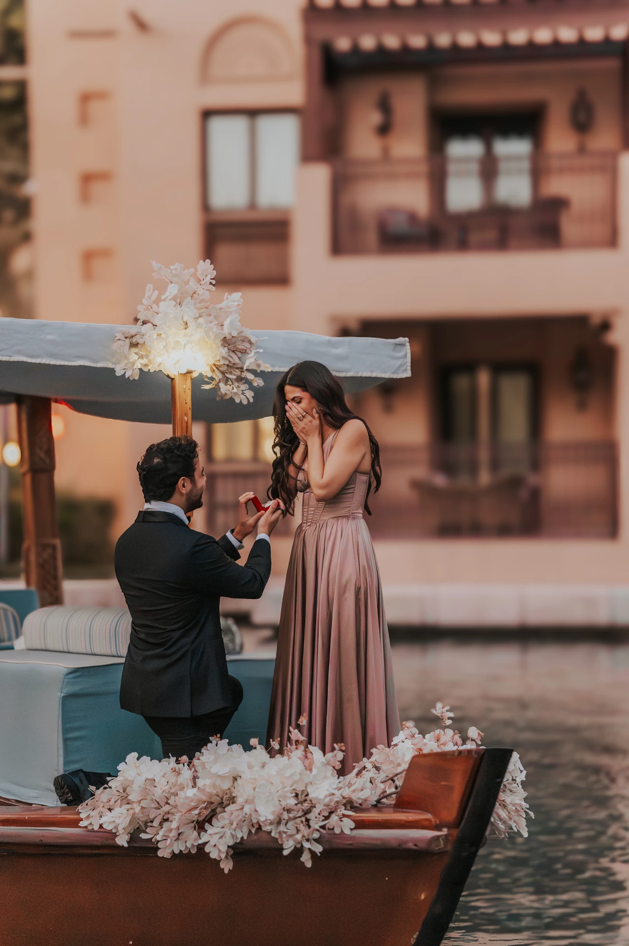 Dubai Photohoot - proposal ring moment A man kneels and presents a ring beside a Dubai resort pool during a photoshoot while his partner smiles at the proposal moment.