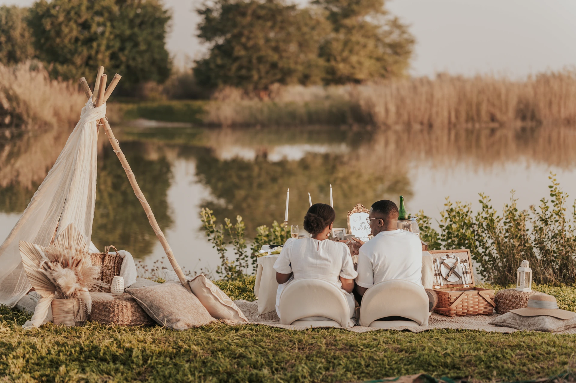 Couple sitting by their Dubai picnic looking over the water after a succesfull proposal