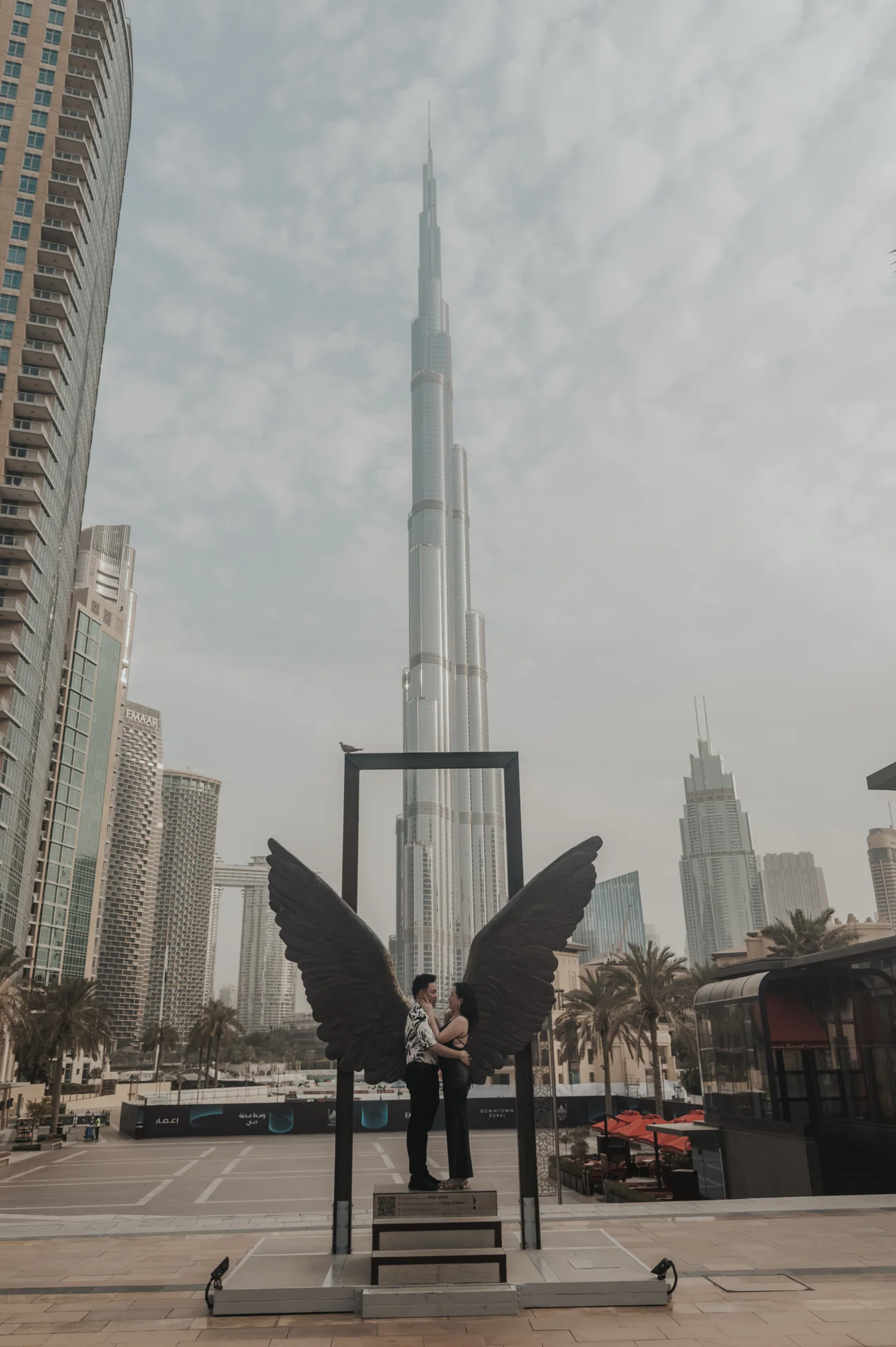 Dubai Proposal Portrait at Wings of Mexico A couple embraces beneath the Wings of Mexico sculpture with Burj Khalifa rising behind their Dubai proposal portrait.
