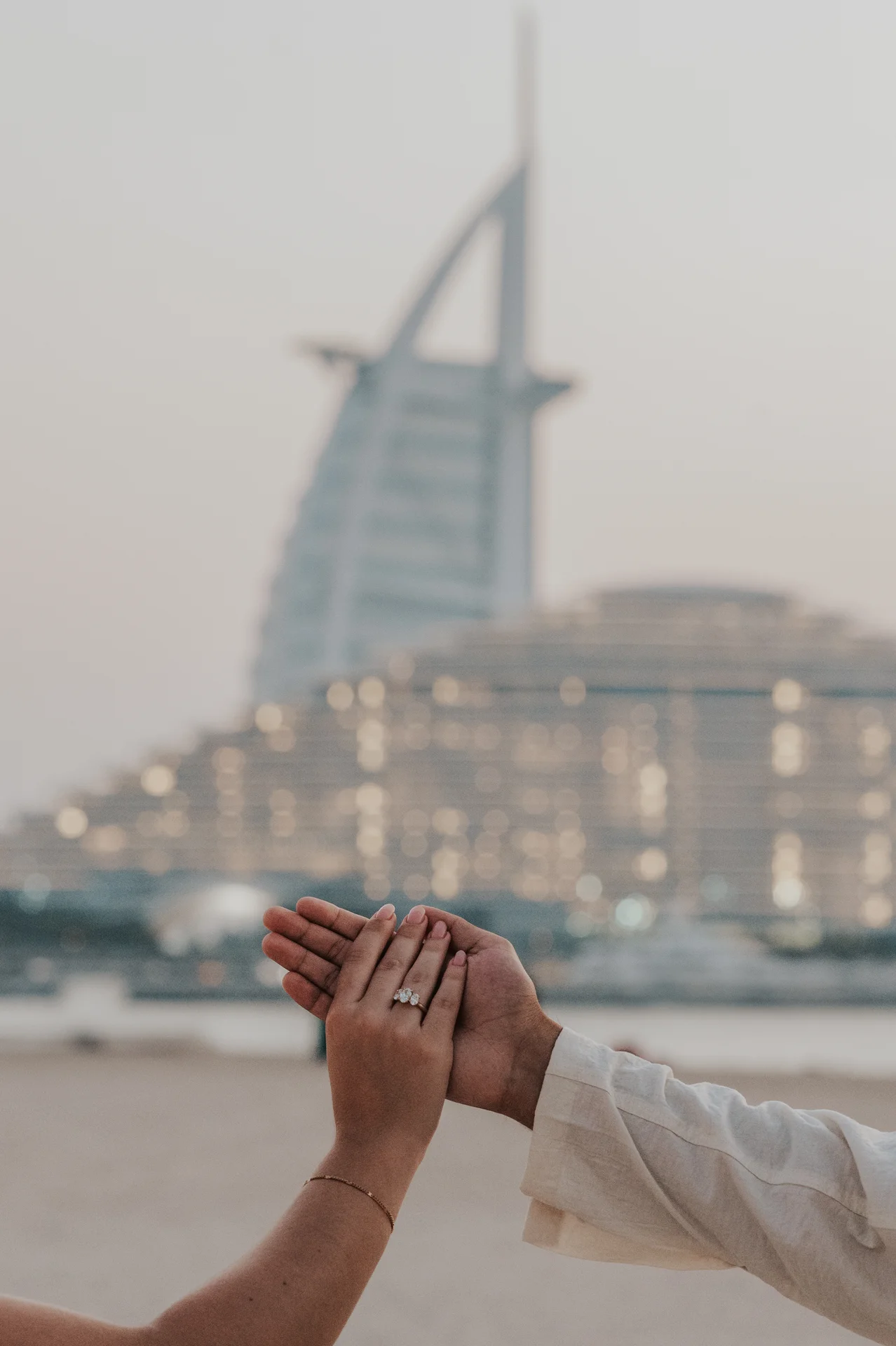 Dubai Proposal Ring Portrait by Burj Al Arab A couple frames an engagement ring between their hands with Burj Al Arab behind them during a Dubai proposal portrait.
