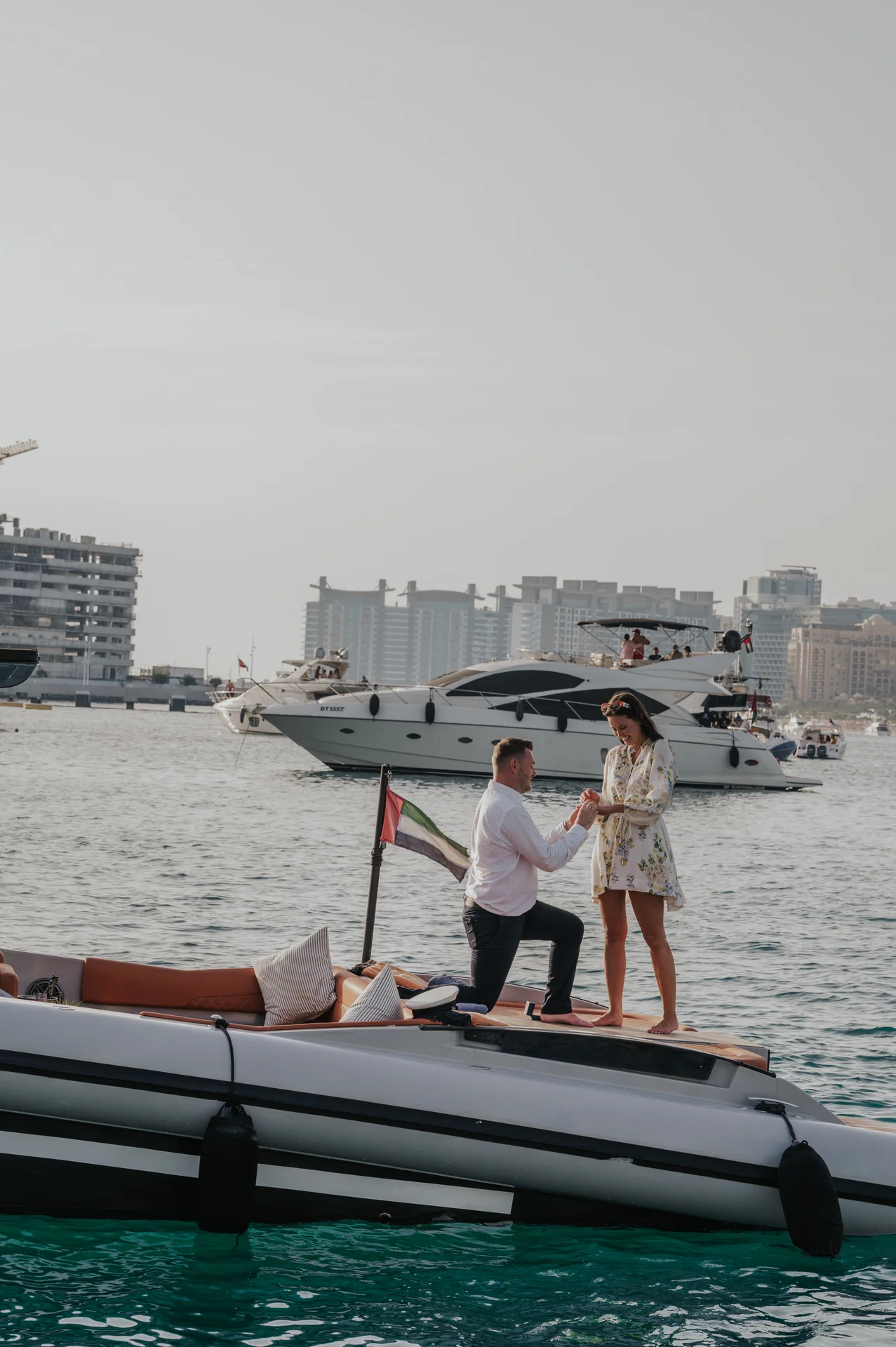 Proposing on a Private Boat in Dubai A man kneels and holds his partner’s hand on a private boat during a waterfront Dubai proposal photoshoot.