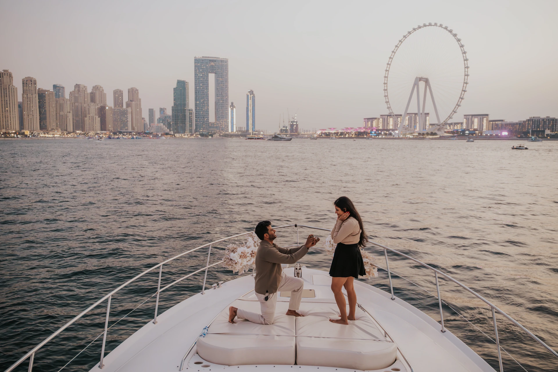 A proposal on a yacht in Dubai with Dubai Marina and Blue Waters in the background.