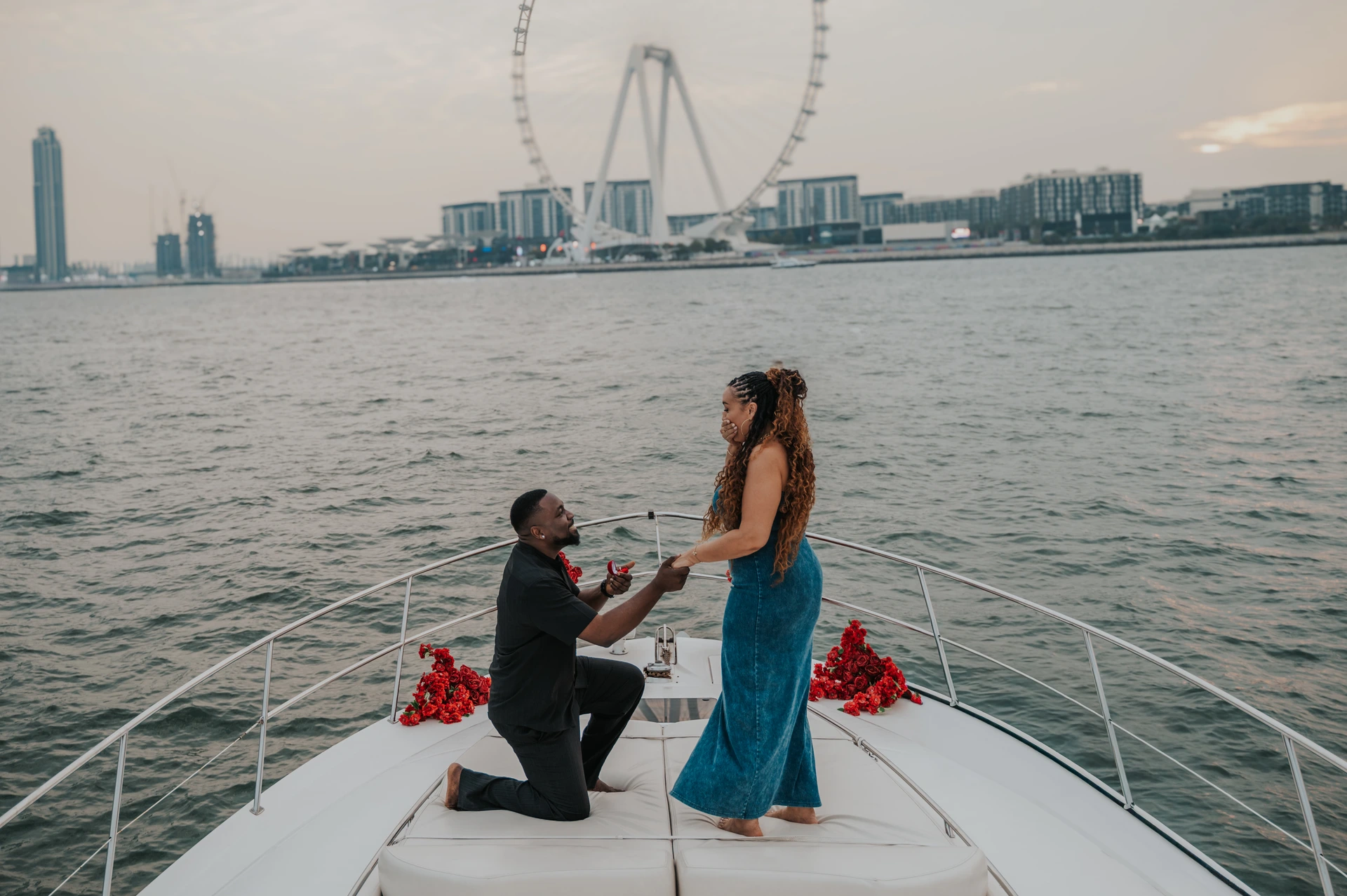 A proposal on a yacht in Dubai with Dubai Marina and Blue Waters in the background.