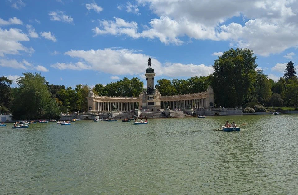 Rowboats cross El Retiro's lake beneath the Alfonso XII monument, introducing a green and architectural Madrid photoshoot route.