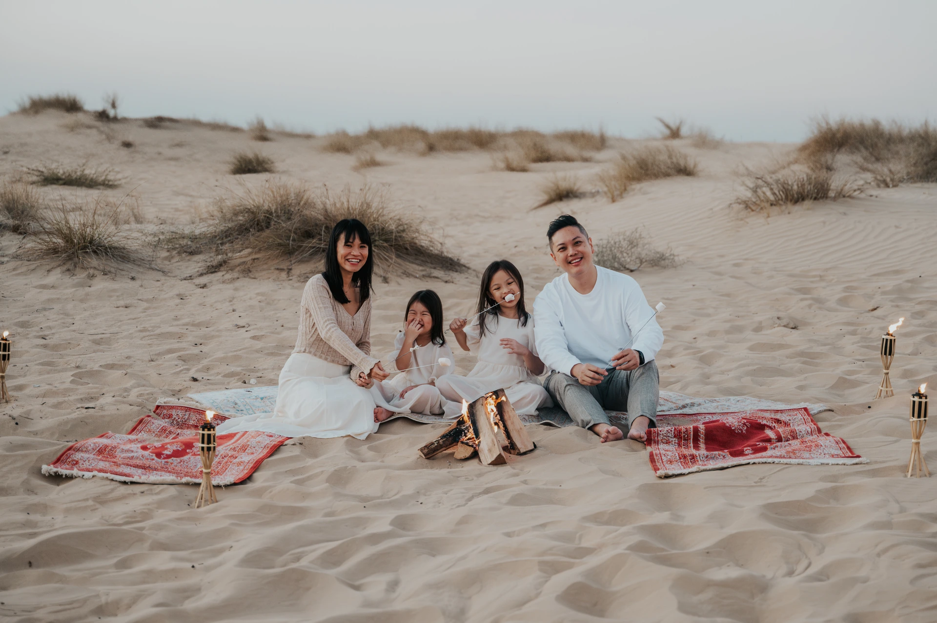 A family standing together on golden Dubai desert dunes during a relaxed family photoshoot at sunset.