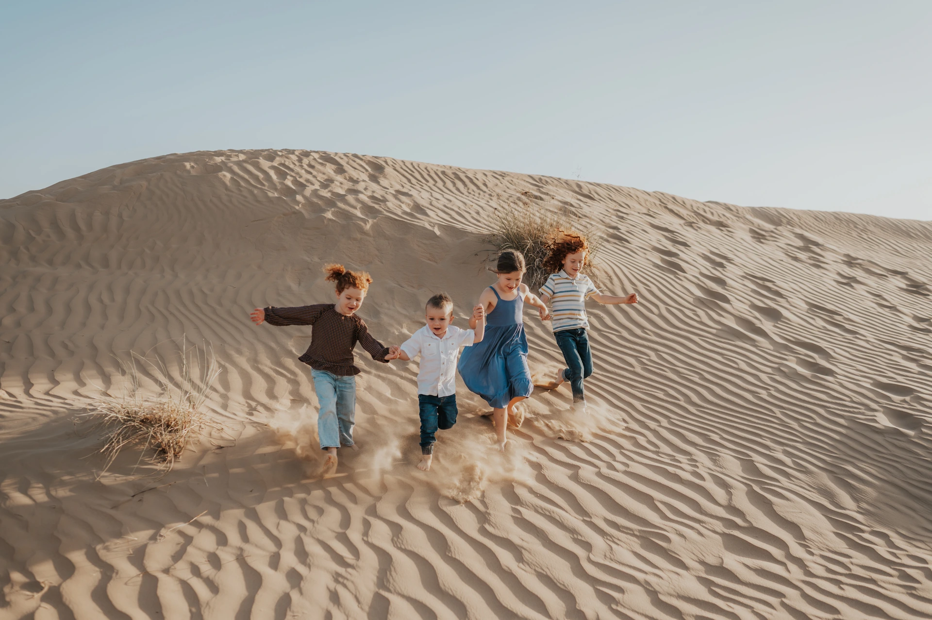 Kids running on desert dunes during a family Dubai activity