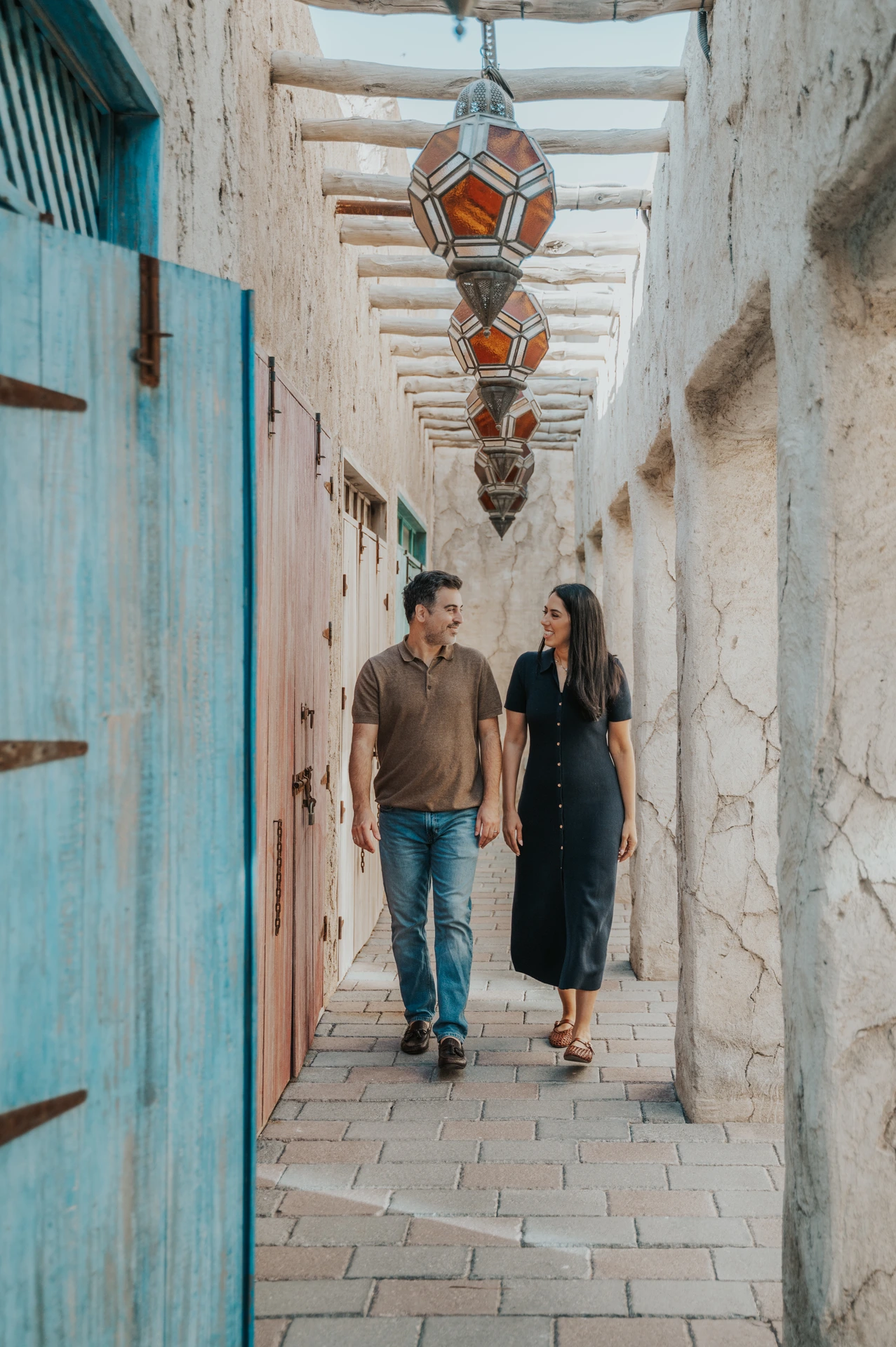 A couple walks through a narrow Old Dubai alley with textured walls during a family photoshoot session.
