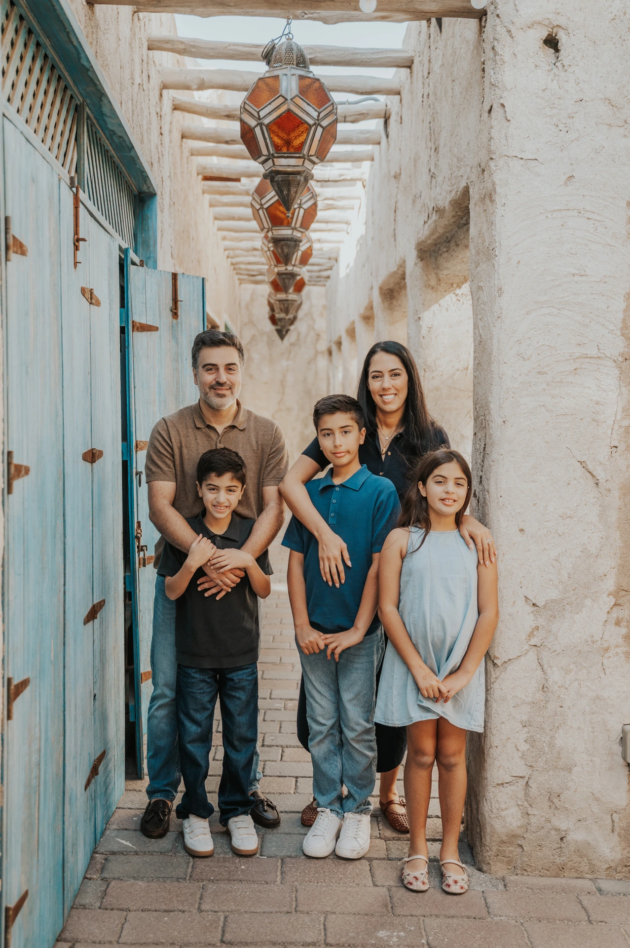 Parents stand with their three children in an Old Dubai alley during a classic family photoshoot portrait.