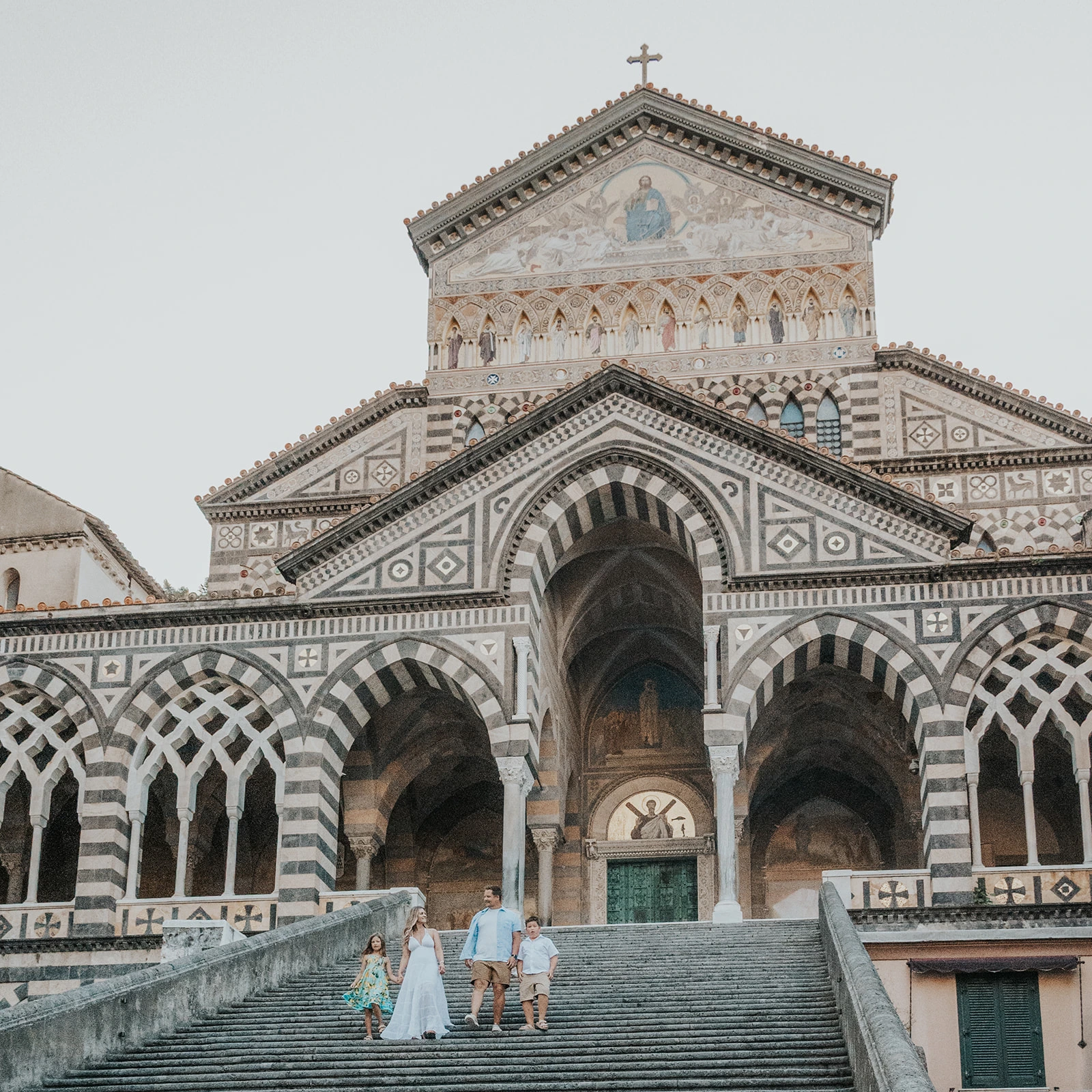 Family on the steps beneath the decorated facade of Amalfi Cathedral