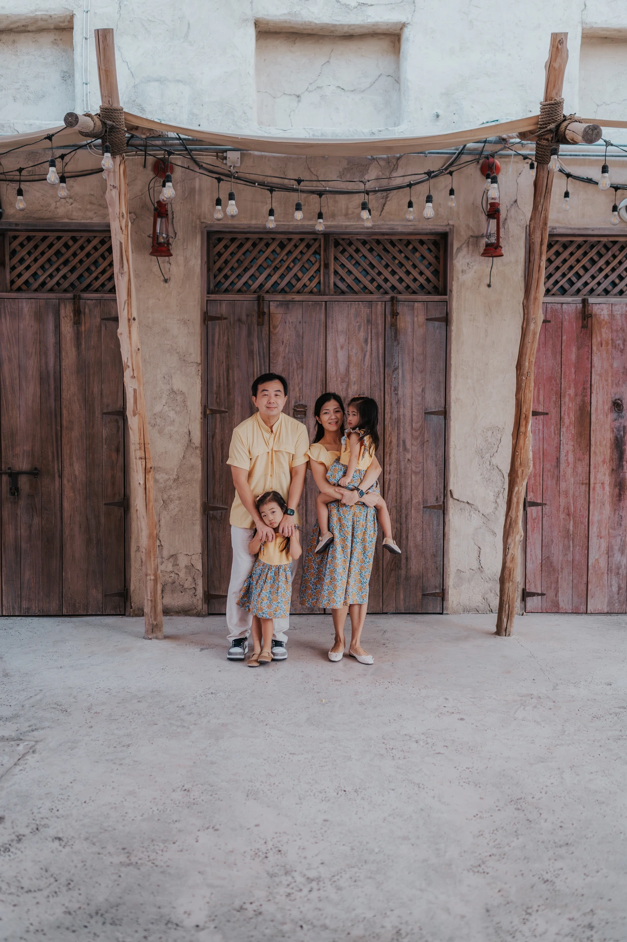A family with two toddlers stands in front of traditional wooden doors in Old Dubai during a family photoshoot.
