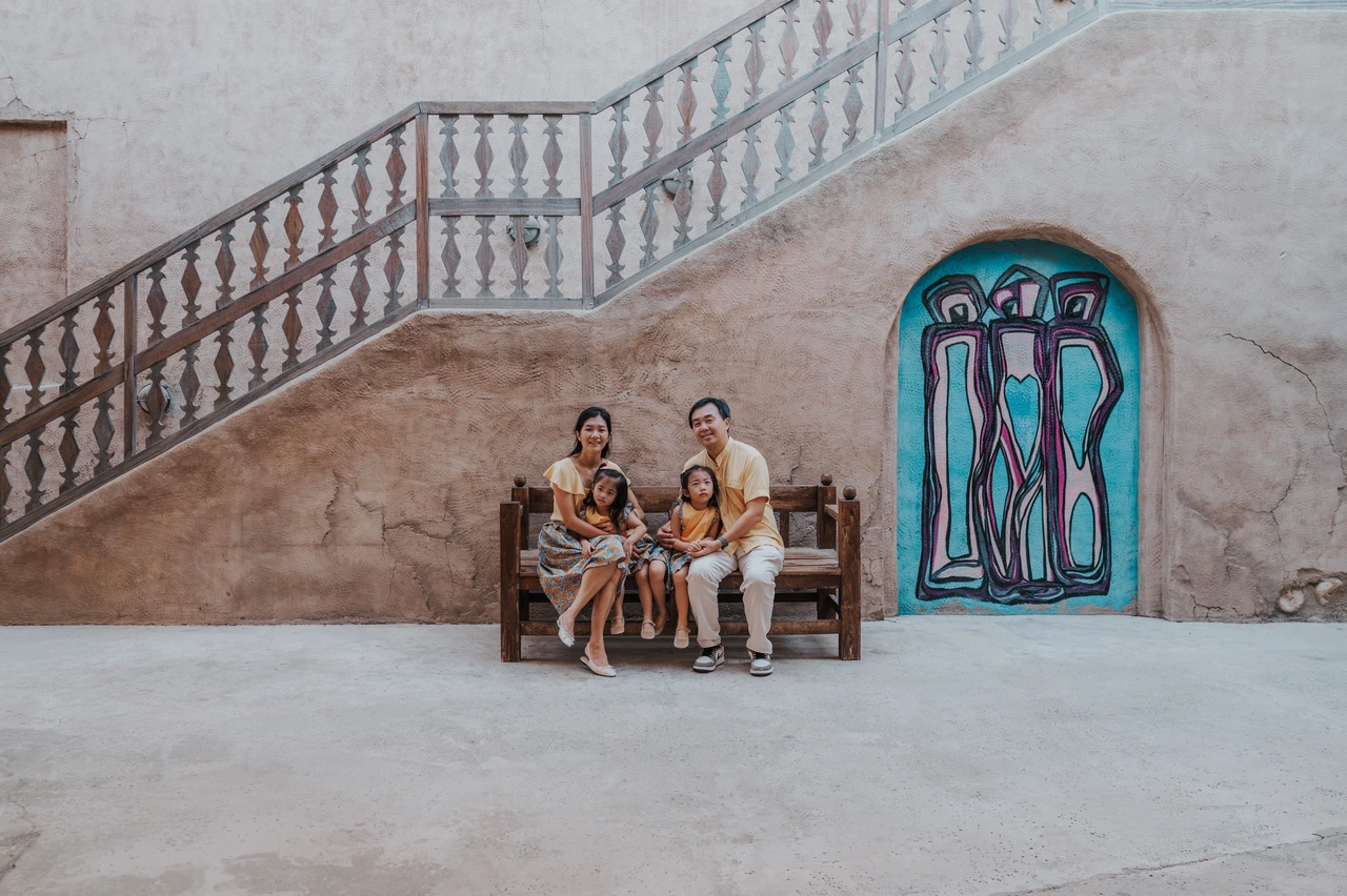 Family photoshoot in Dubai - old town bench portrait A family sits together on a bench in an Old Dubai courtyard during a lifestyle family photoshoot session.