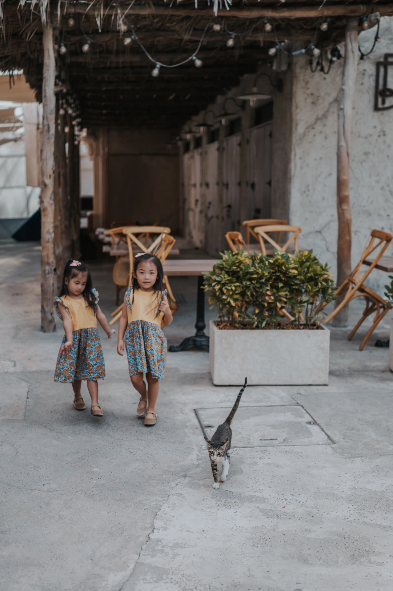 Two little girls walk together side by side through an Old Dubai lane during a natural toddler family photoshoot.
