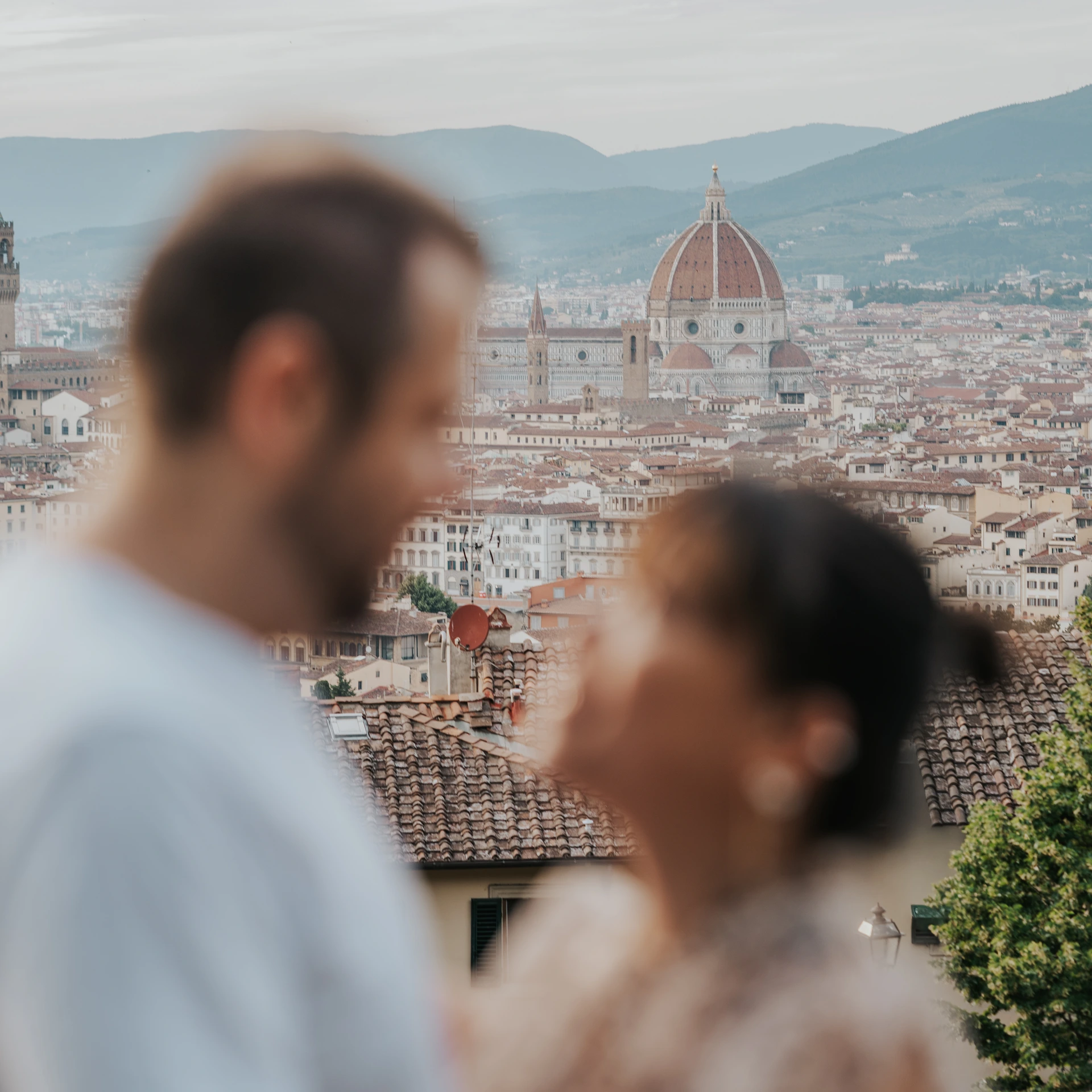 La cupola del Duomo di Firenze è a fuoco dietro i volti sfocati di una coppia.