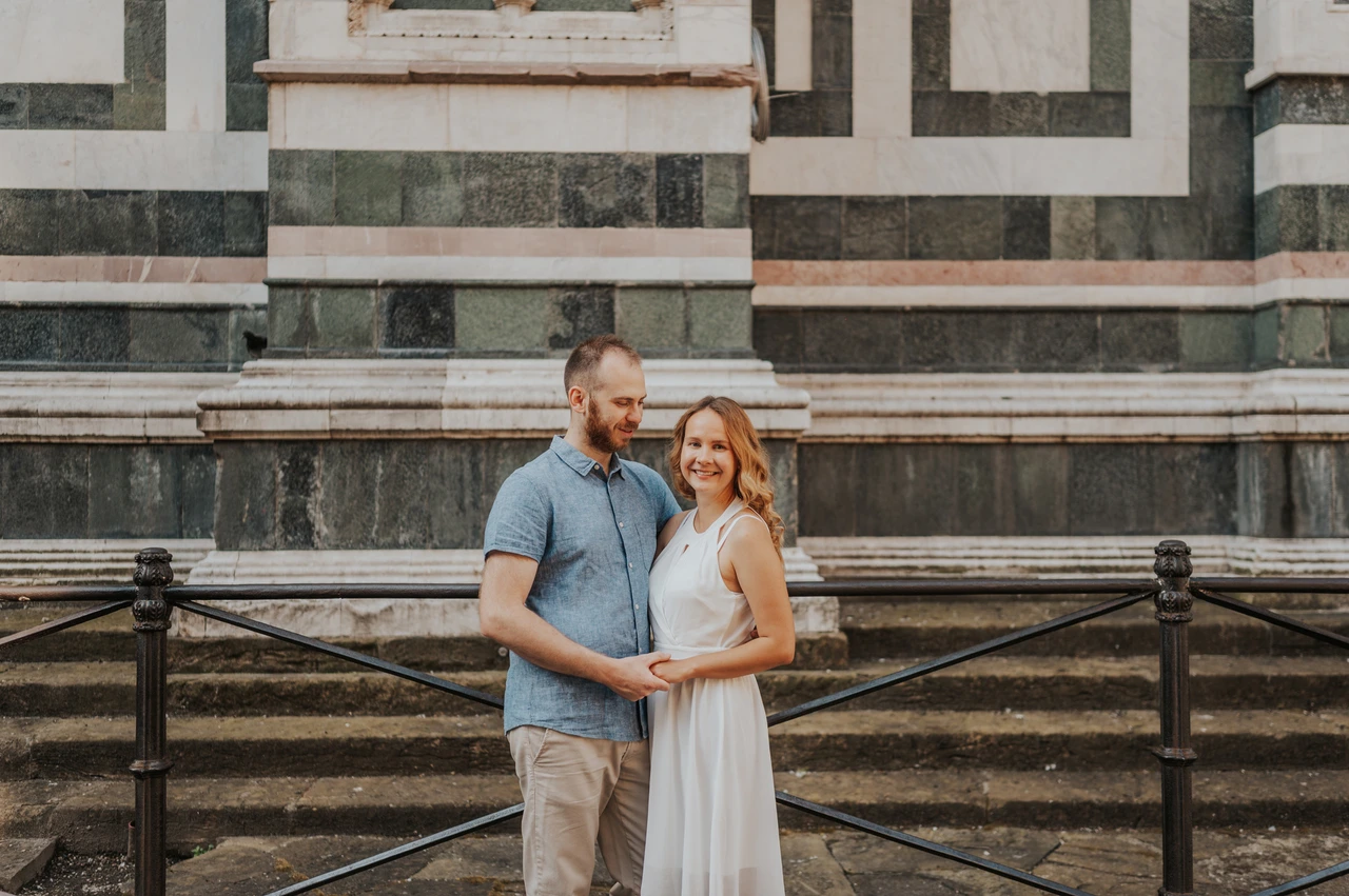 A close marble-wall portrait during a Florence couple photoshoot The couple smile together beside a railing with green and white marble behind them during their Florence couple photoshoot.