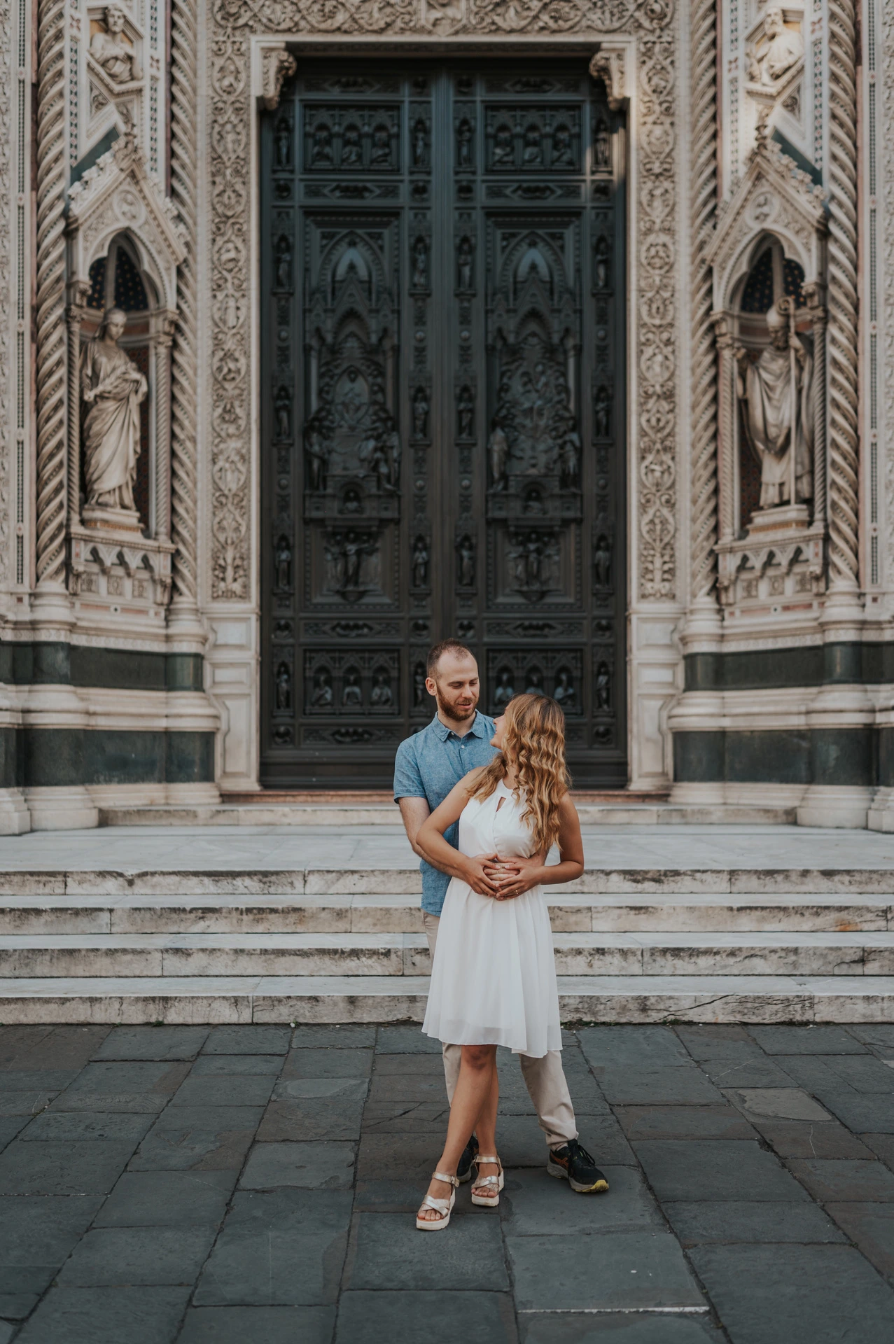 The couple embrace in front of the Duomo’s decorated entrance during their Florence couple photoshoot.