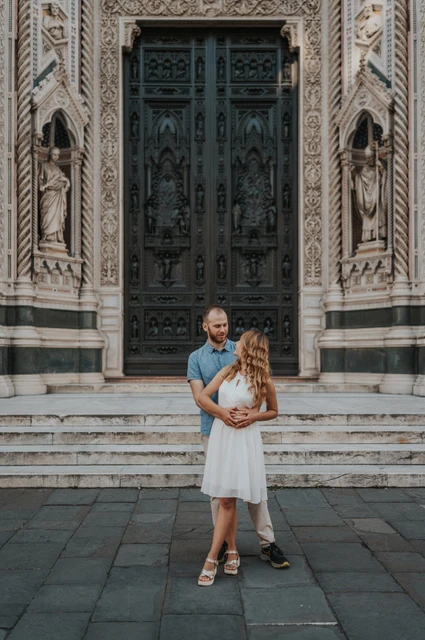 An embrace by the Duomo entrance during a Florence photoshoot The couple embrace in front of the Duomo’s decorated entrance during their Florence couple photoshoot.
