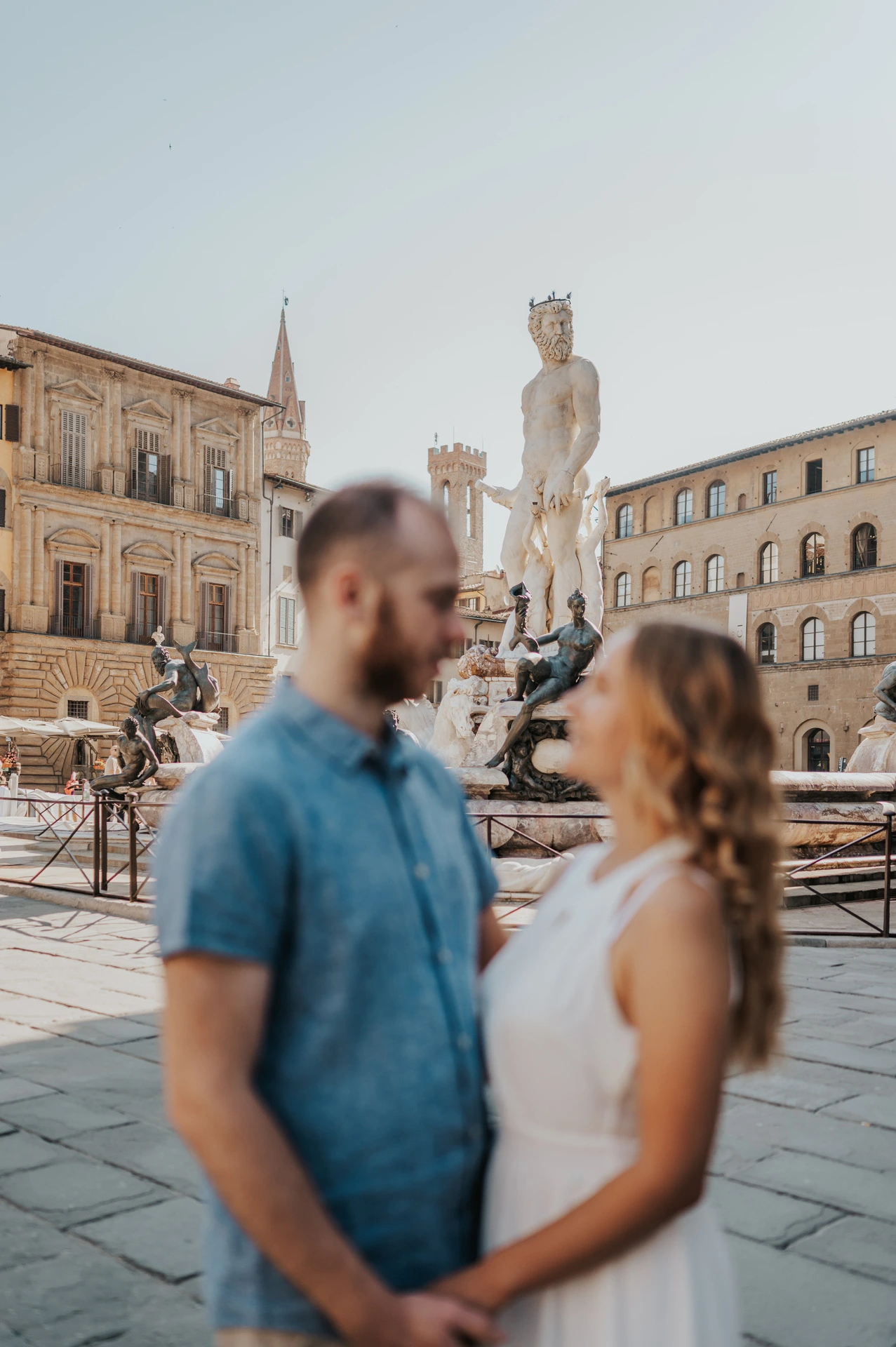 The Neptune Fountain remains in focus behind the softly blurred couple during their Florence couple photoshoot.