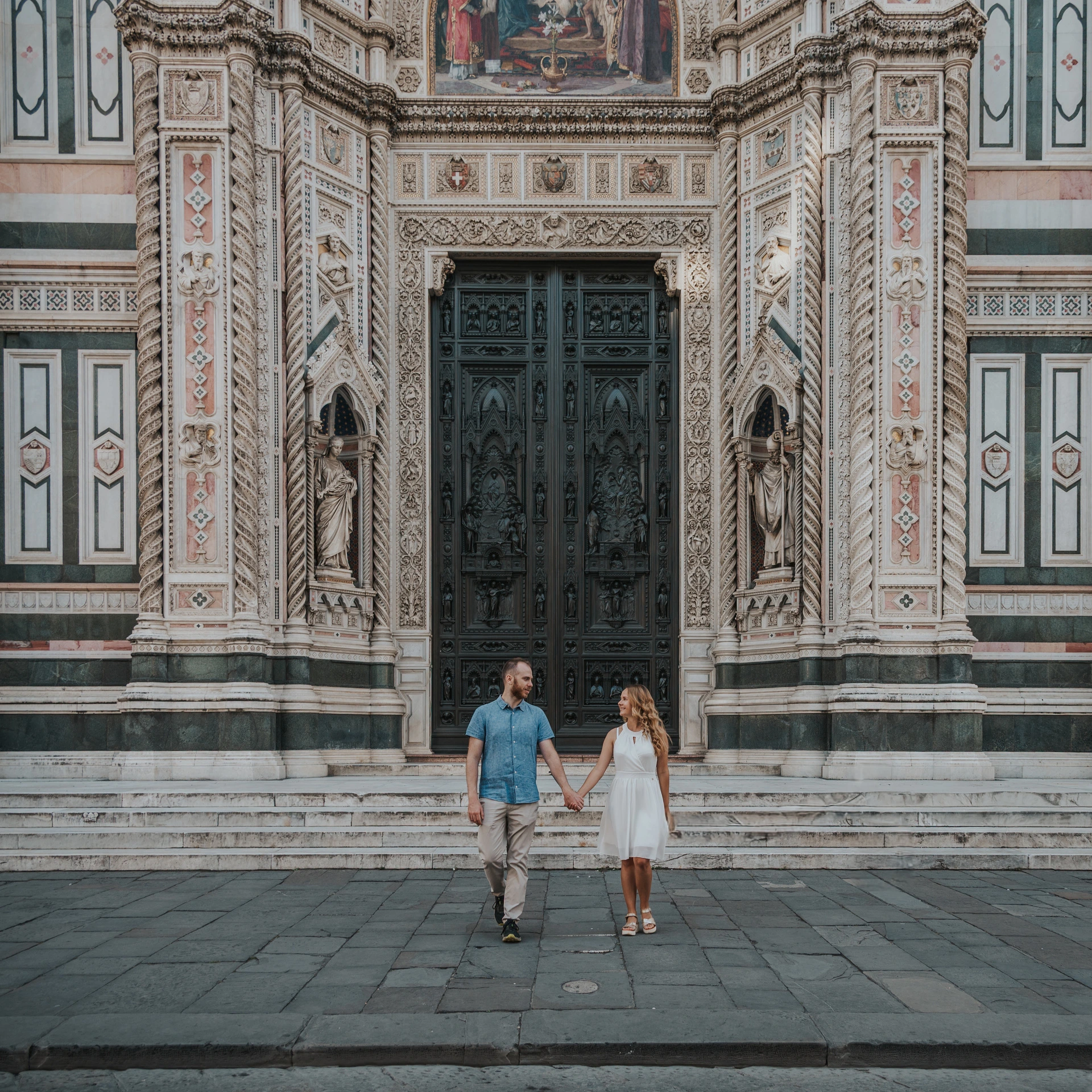A square photograph shows the couple beneath the Duomo’s decorated doorway during their Florence couple photoshoot.