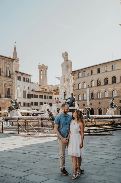 Florence couple photoshoot in Piazza della Signoria The couple embrace in Piazza della Signoria, with the Neptune Fountain and historic buildings behind them, during their Florence photoshoot.
